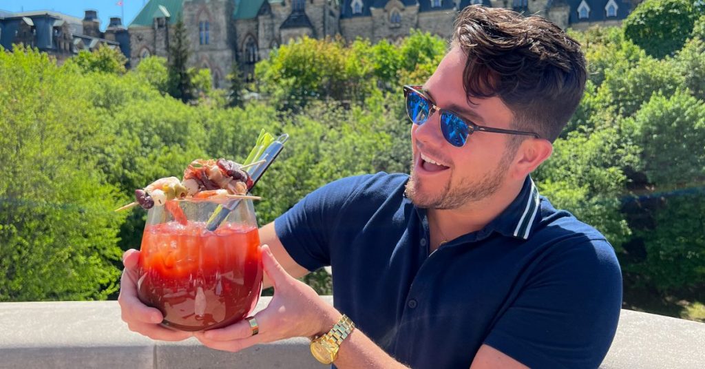 Man holding a large cocktail at a Ottawa patio