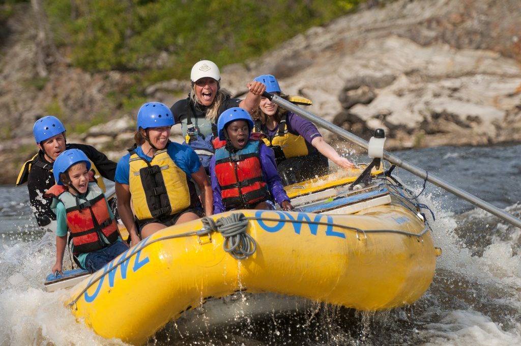 a raft guide leads 5 rafters through rapids on a yellow blow up raft