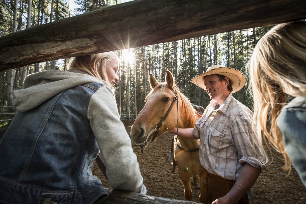 A girl greats a horse as a part of the Banff Trail Riders Adventures in Alberta, Canada