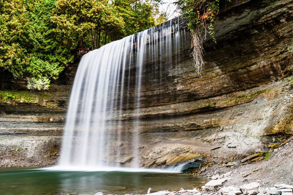 Long time exposure of beautiful Bridal Veil Falls on Manitoulin Island surrounded bei trees and lake and ability to walk behind the falls.