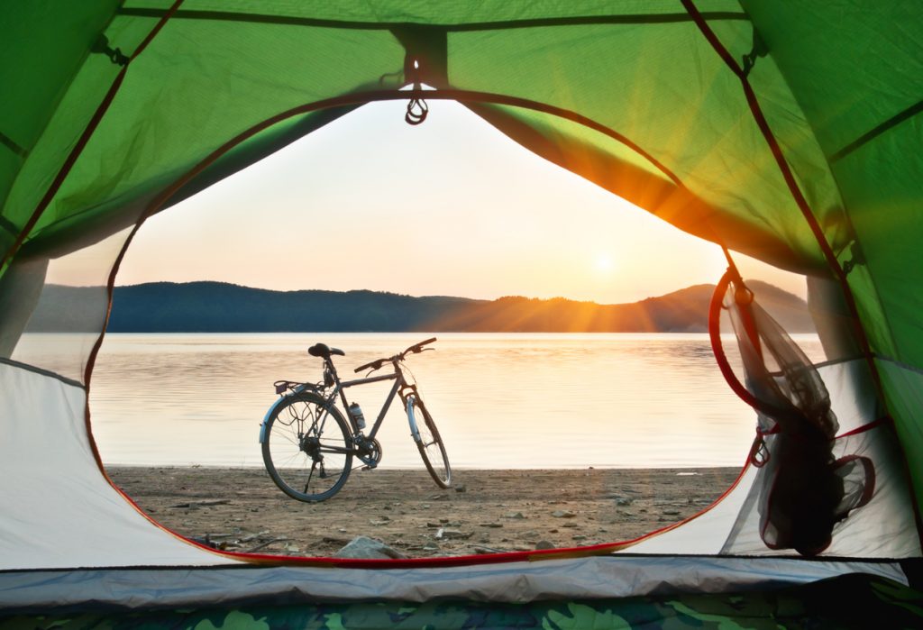 View of a bike on a beach out a tent door during a bikpacking trip