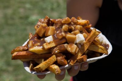 Closeup to a serving of Poutine being held by a woman