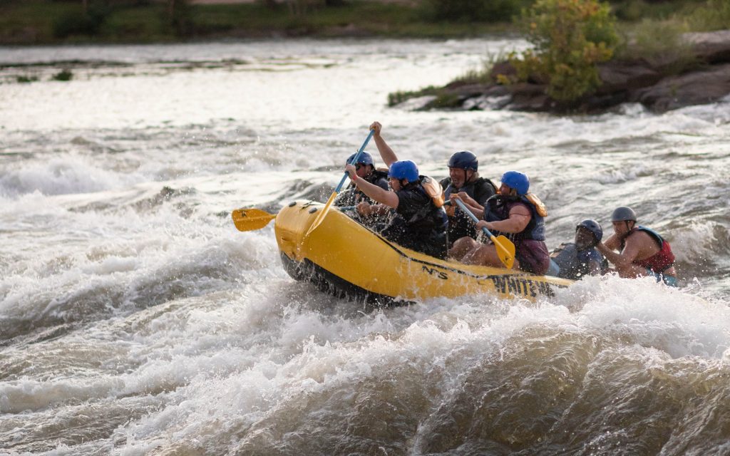 A rafting guide instructs paddlers over white water in a yellow raft