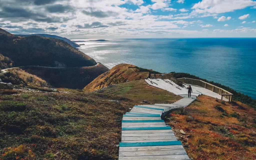 Wooden steps cascasde down rolling hills towards blue ocean waters aloing the Cabot Trail in Nova Scotia.