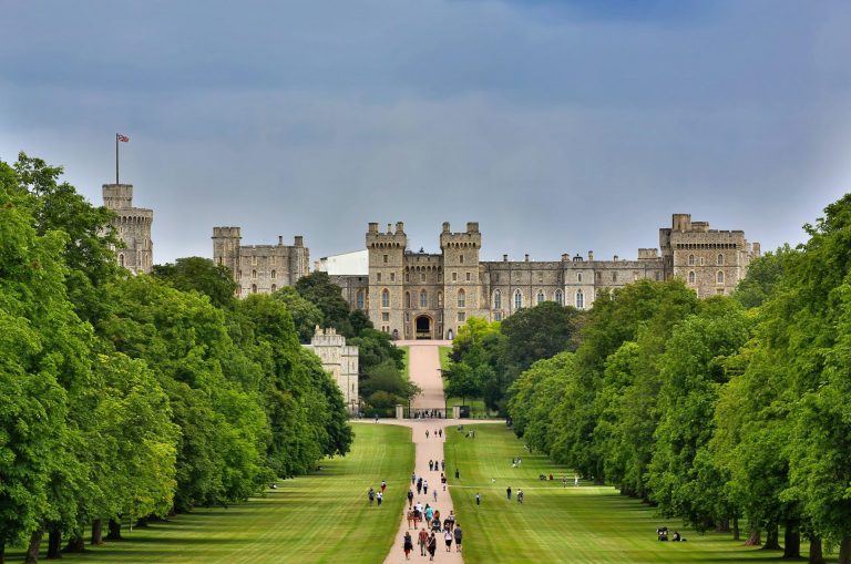 Crowds of people walking on the stone path and grass heading towards windsor castle in England