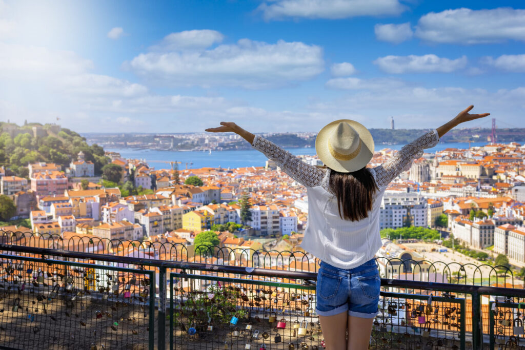 woman overlooks the colorful old town Alfama of Lisbon city, Portugal, and castle Sao Jorge on her sightseeing trip