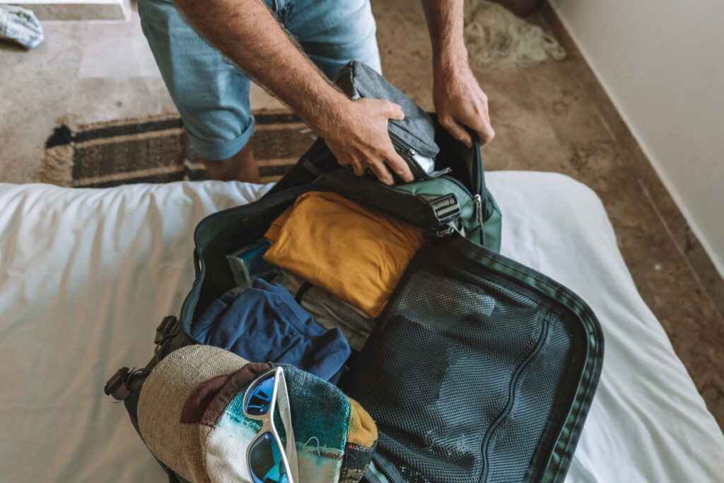 Top view of male traveler packing for a trip, puts clothes in a du