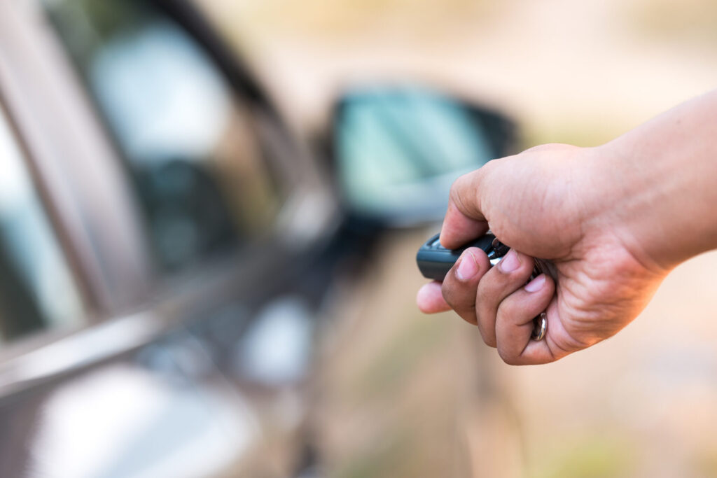 Man's hand pushing unlock button on car remote