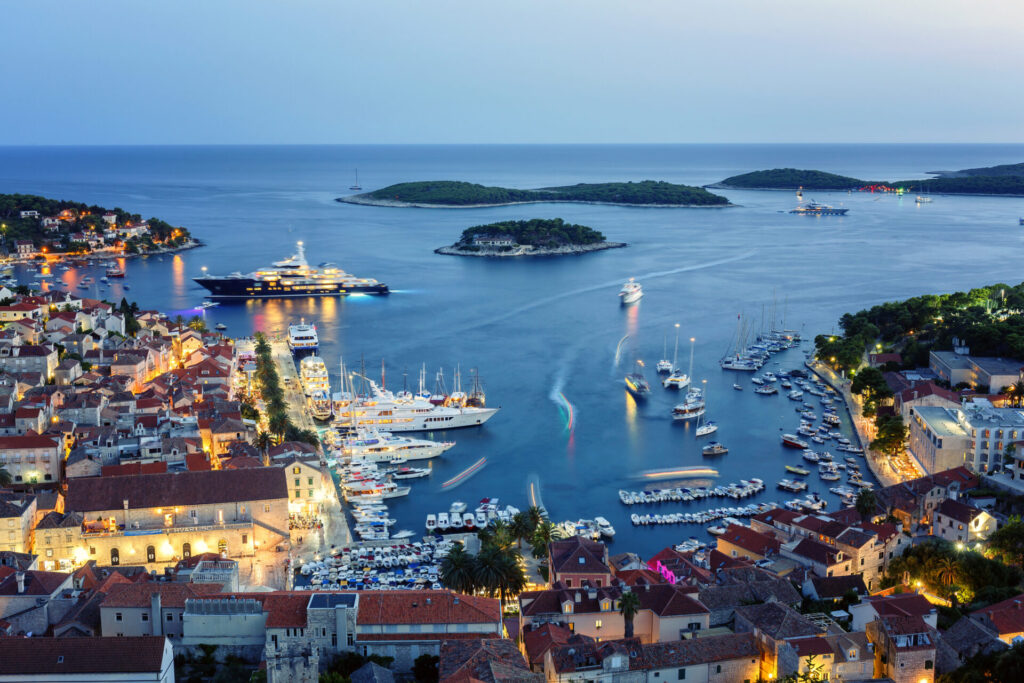 View of the illuminated old town Hvar and the harbor with Pakleni Islands at dusk