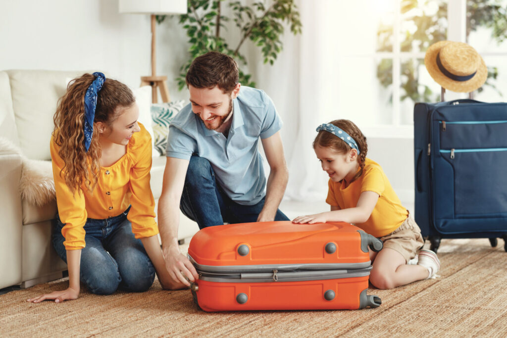 Happy parents with daughter with suitcase setting off for journey