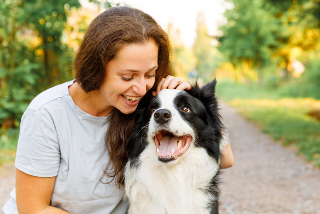 Smiling woman playing with cute border collie