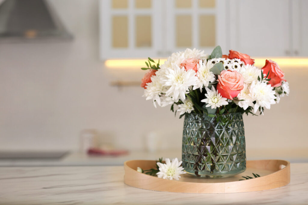 Vase with beautiful flowers on table in kitchen,