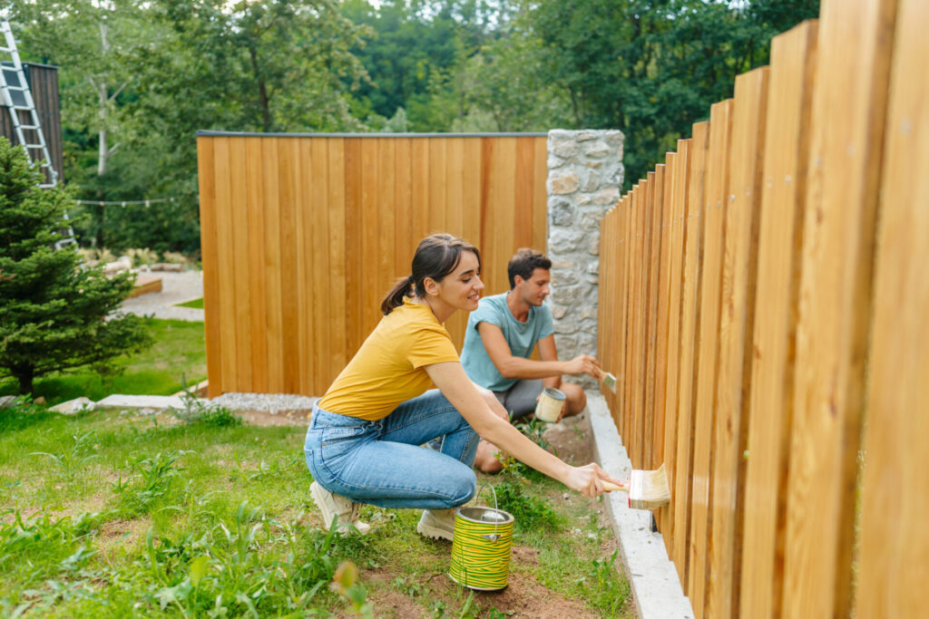 Couple painting a picket fence