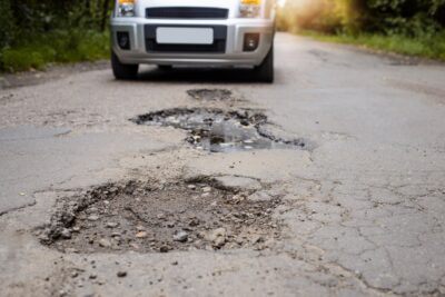 A low shot of a vehicle approaching a pothole