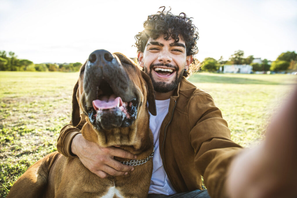 Young happy man taking selfie with his dog in a park