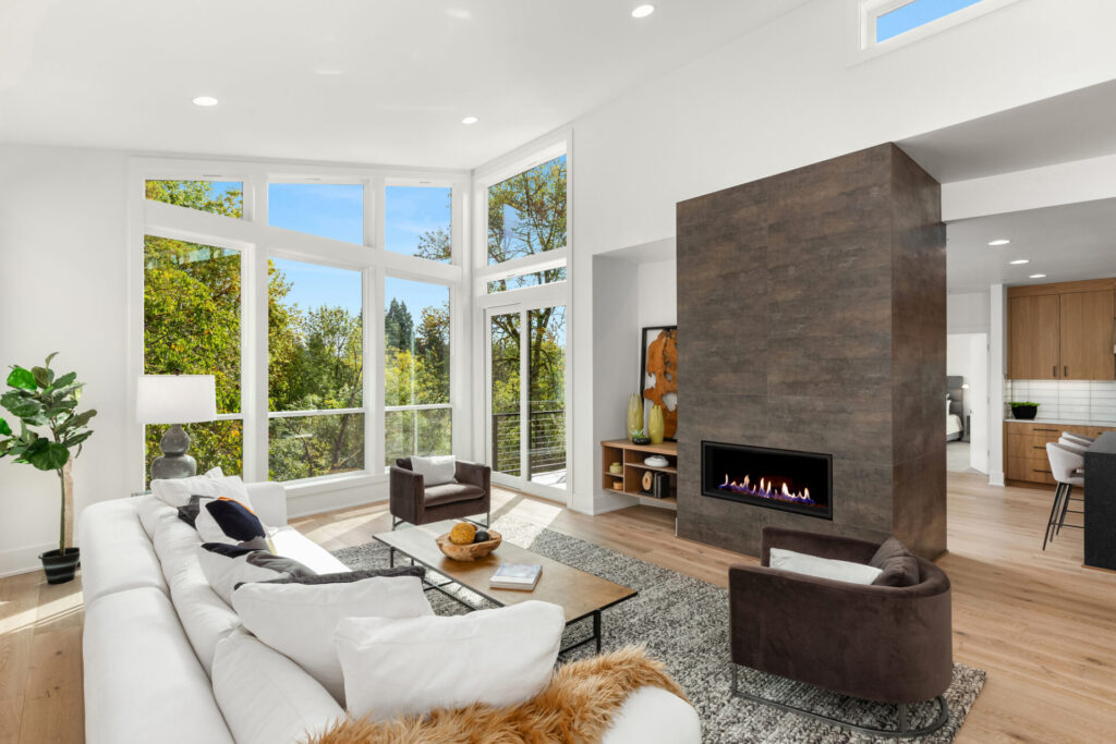 Beautiful living room interior with hardwood floors and fireplace in new modern luxury home. Features wall of windows and abundant natural light.