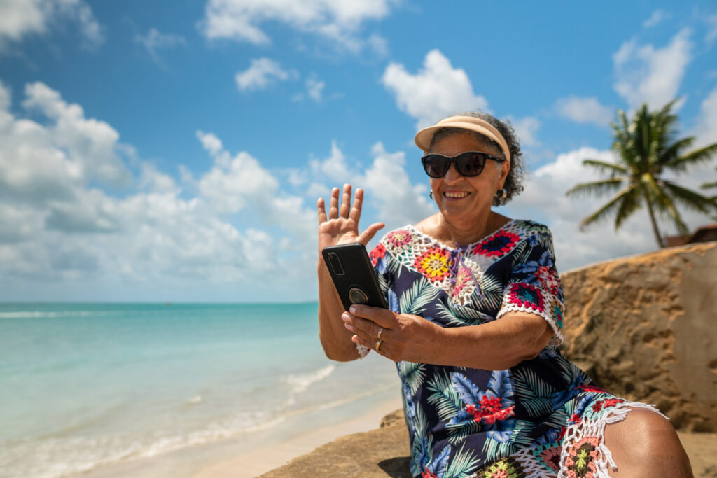 Grandma waving by video call on tropical beach