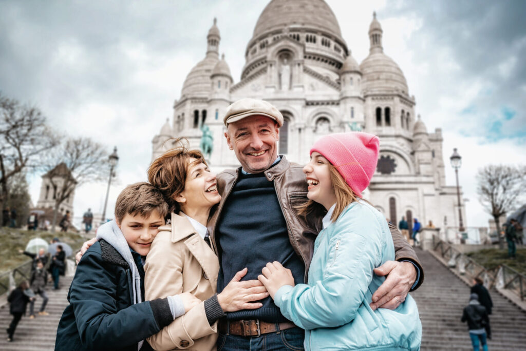 happy french family standing embraced in front of Sacre Coeur in Monmartre in Paris