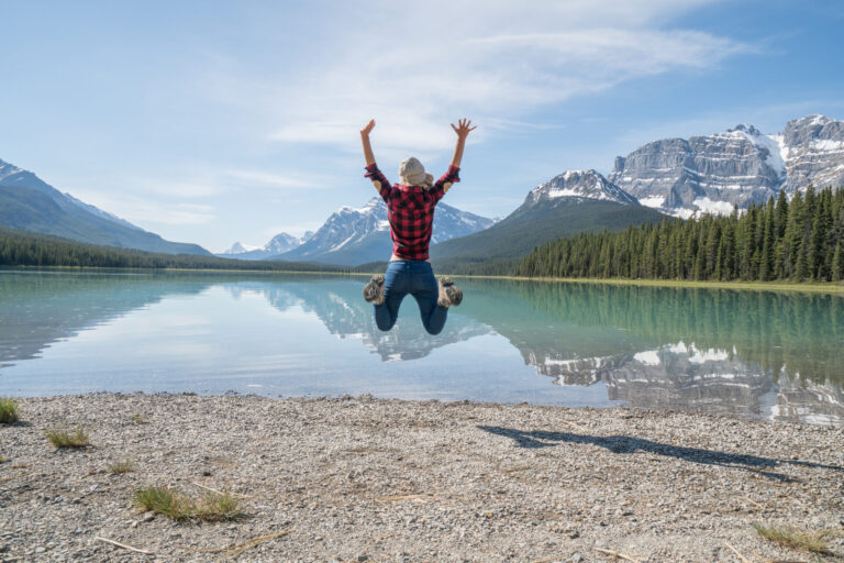 Young woman jumping mid-air by the mountain lake