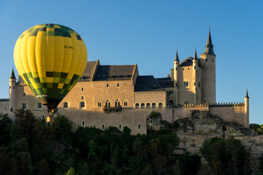 Alcazar fortress of segovia at sunrise with various hot air balloons in the sky, listed world Heritage centre by UNESCO