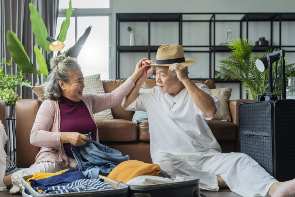 senior couple packing cloth and stuff for a trip together,happiness asian old age retired mature adult enjoy arrange cloth together on floor at living room at home interior background