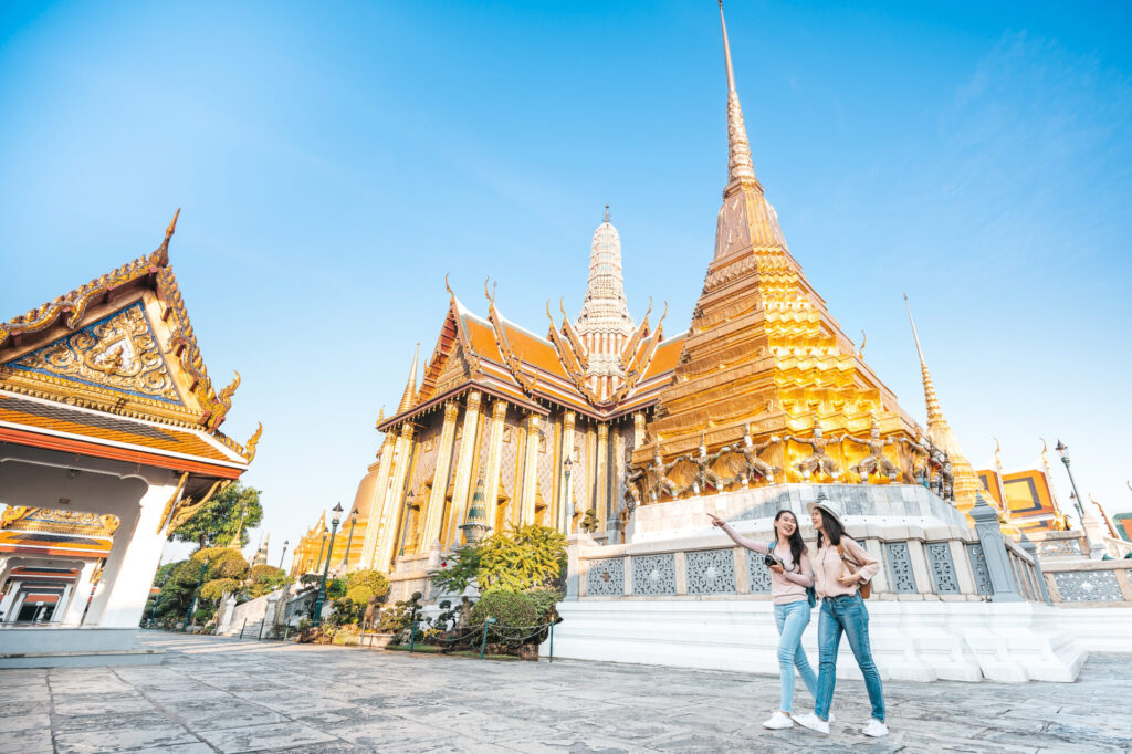 women friends enjoy sightseeing while travel in temple of the emerald buddha in Thailand