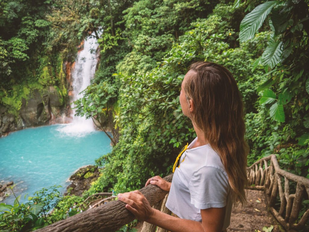 woman contemplating turquoise waterfall in Costa Rica