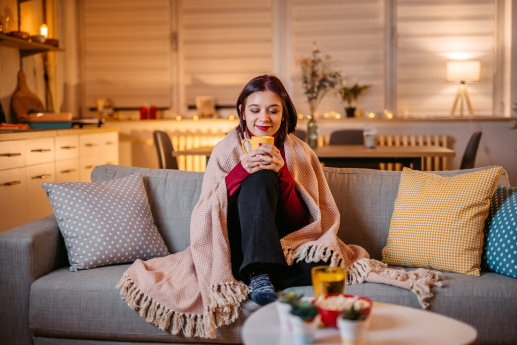 woman drinking hot tea wrapped in blanket