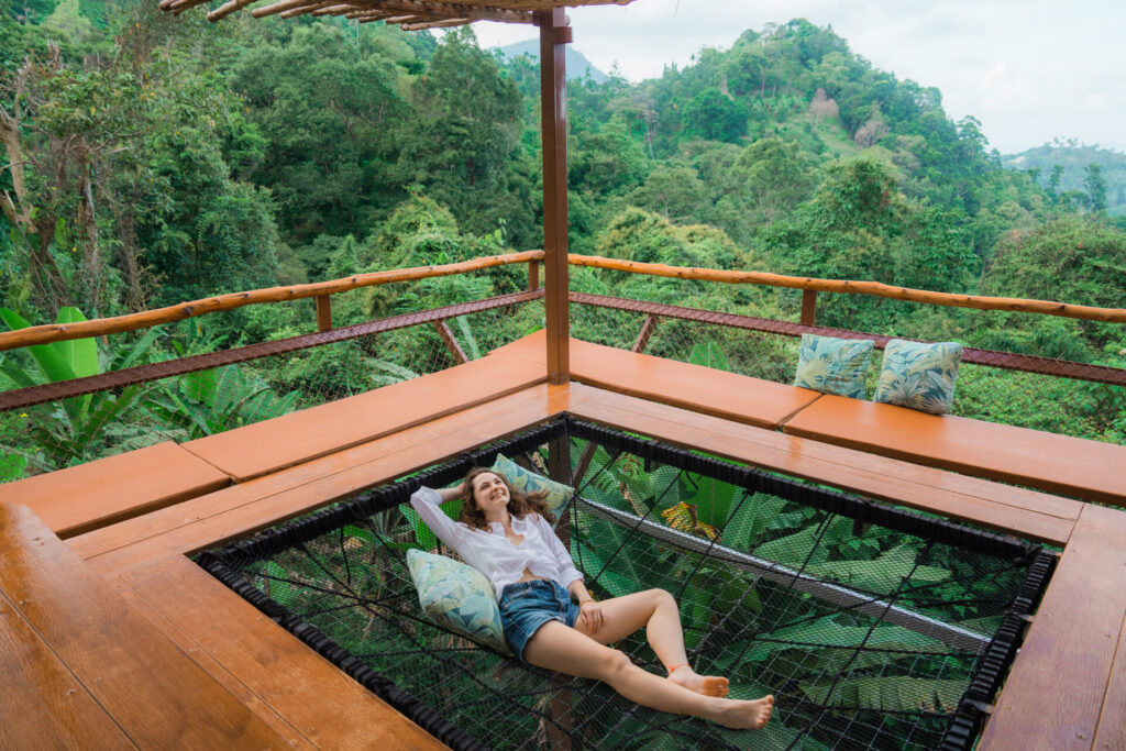 Woman laying in hammock on the terrace and looking at jungles