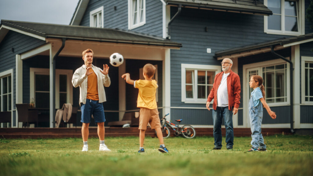 Family Spending Leisure Time Outside with Kids, Grandfather Playing with Ball with a Children. People Throwing the Ball Between Each Other, Having Fun on a Lawn in Their Front Yard.