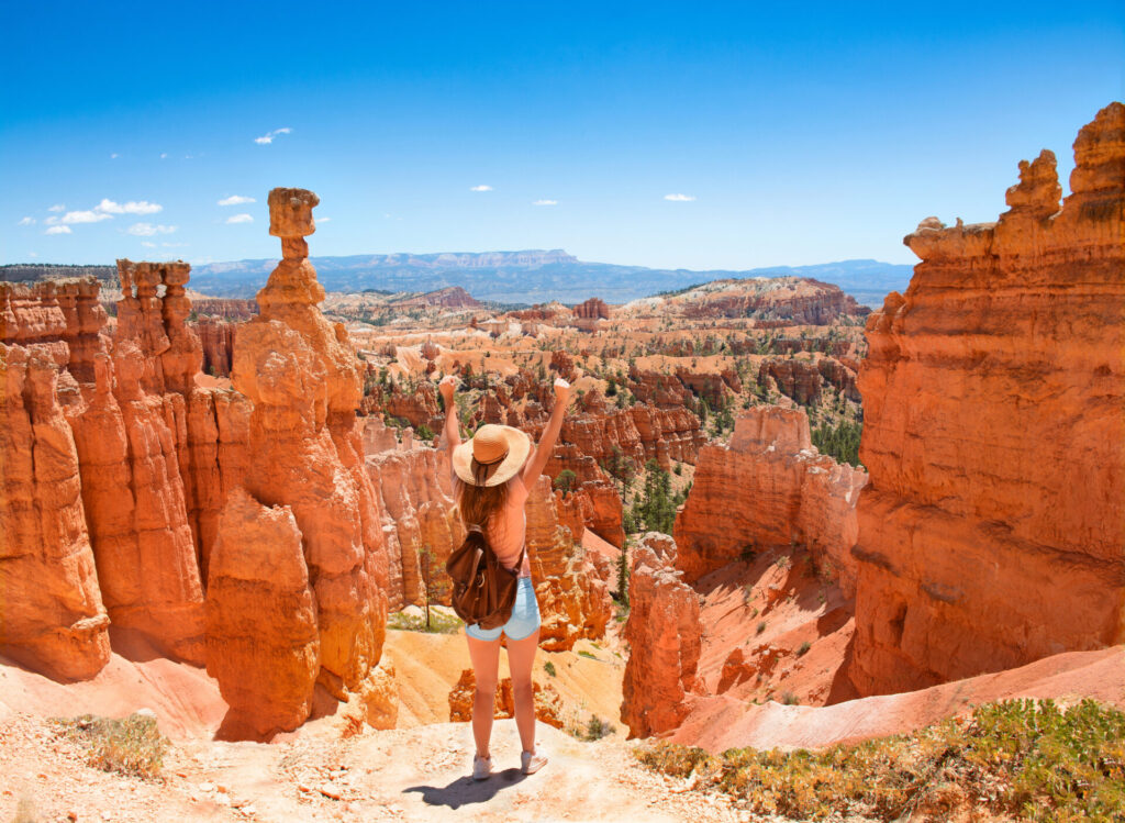 Young woman with raised hands relaxing on top of the mountain.