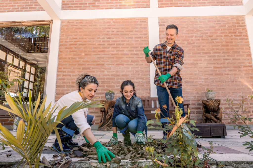 The cheerful family raking autumn leaves